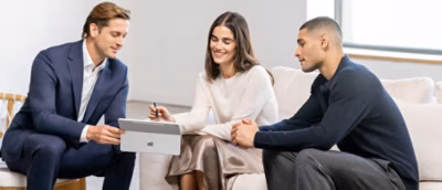 Two people collaborating at a desk, reviewing content on a laptop.