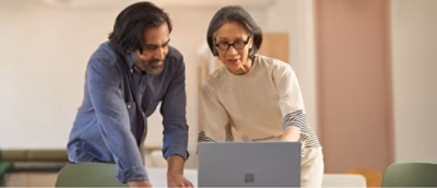 A person and another person looking at a computer