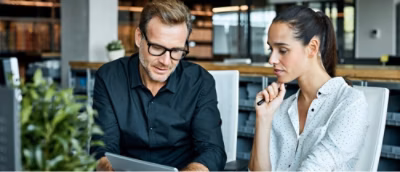 A man and woman looking at a tablet.