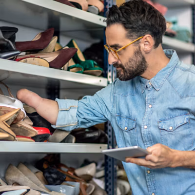 Businessman with a physical disability examining shoes at studio.