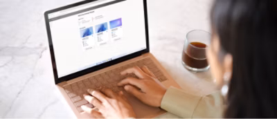 A girl is typing on a computer while having a cup of black coffee.