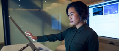 A women with blue shirt working in desktop at office.