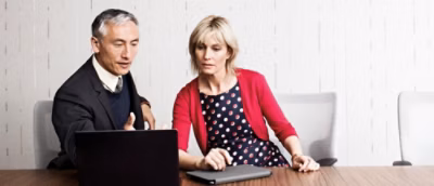 A man and woman looking at a laptop.
